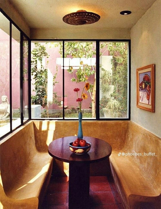 Dining area with natural lighting, wraparound seating, red flooring, and small circular table.